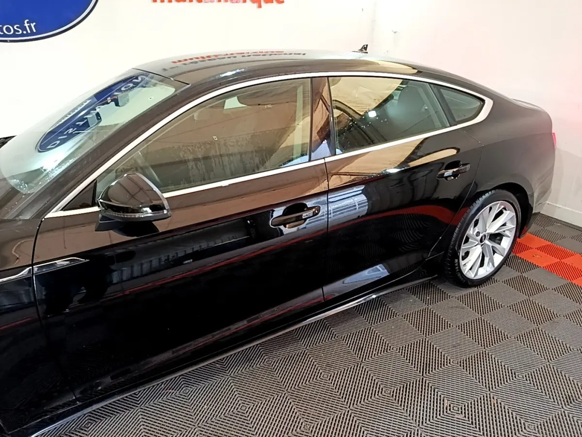 Profil côté gauche d'une Audi A5 noire brillante, mettant en valeur ses lignes fluides et ses jantes argentées.