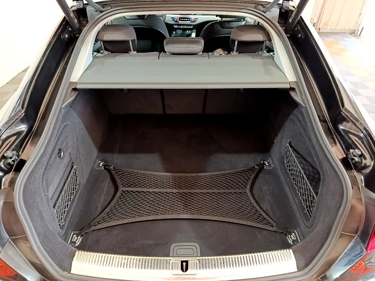 Coffre ouvert noir d'Audi A5 35 TFSI 2021 avec filet de rangement et tablette de séparation visible depuis l'arrière.