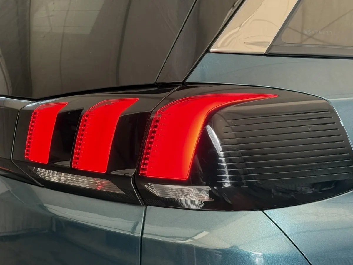 Gros plan sur le feu arrière droit rouge et noir du Peugeot 5008 bleu, soulignant ses lignes modernes et anguleuses.