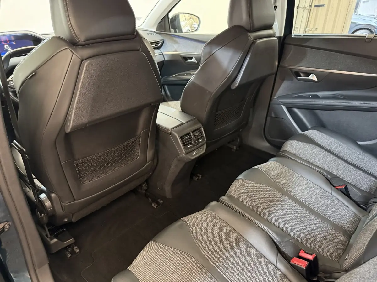 Vue intérieure arrière côté droit du Peugeot 5008 bleu, montrant les sièges tissu et cuir et les dossiers des sièges avant en cuir noir.