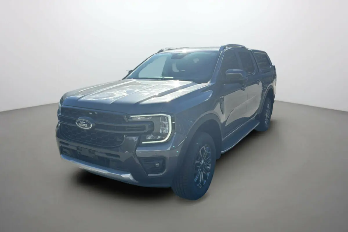 Ford Ranger 3/4 avant droit gris carbone avec hard-top vitré et jantes alu 18 pouces sur fond neutre.