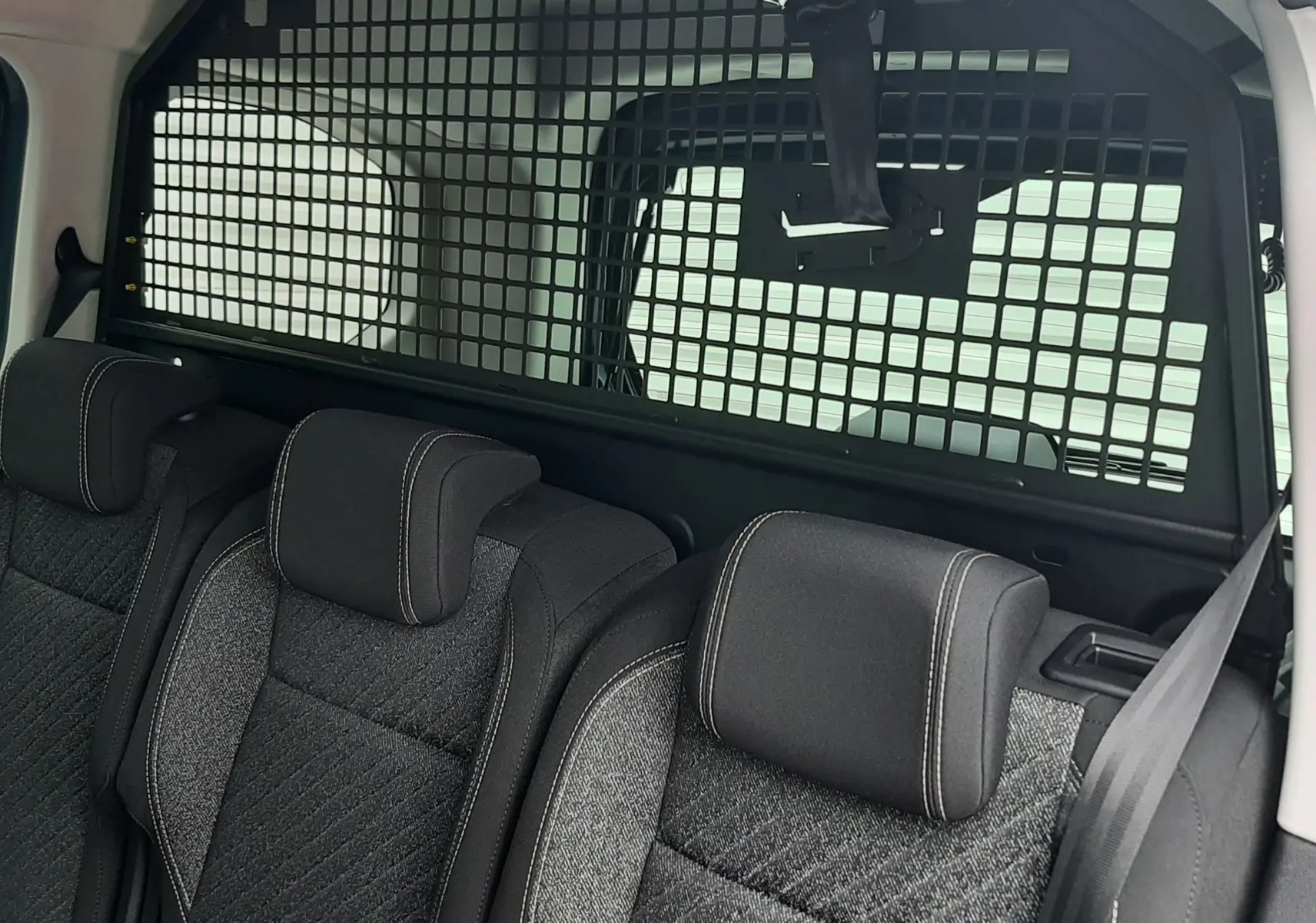 Vue intérieure arrière du Peugeot Rifter Bleu Kiama avec séparation grillagée entre les sièges et l'espace de chargement.