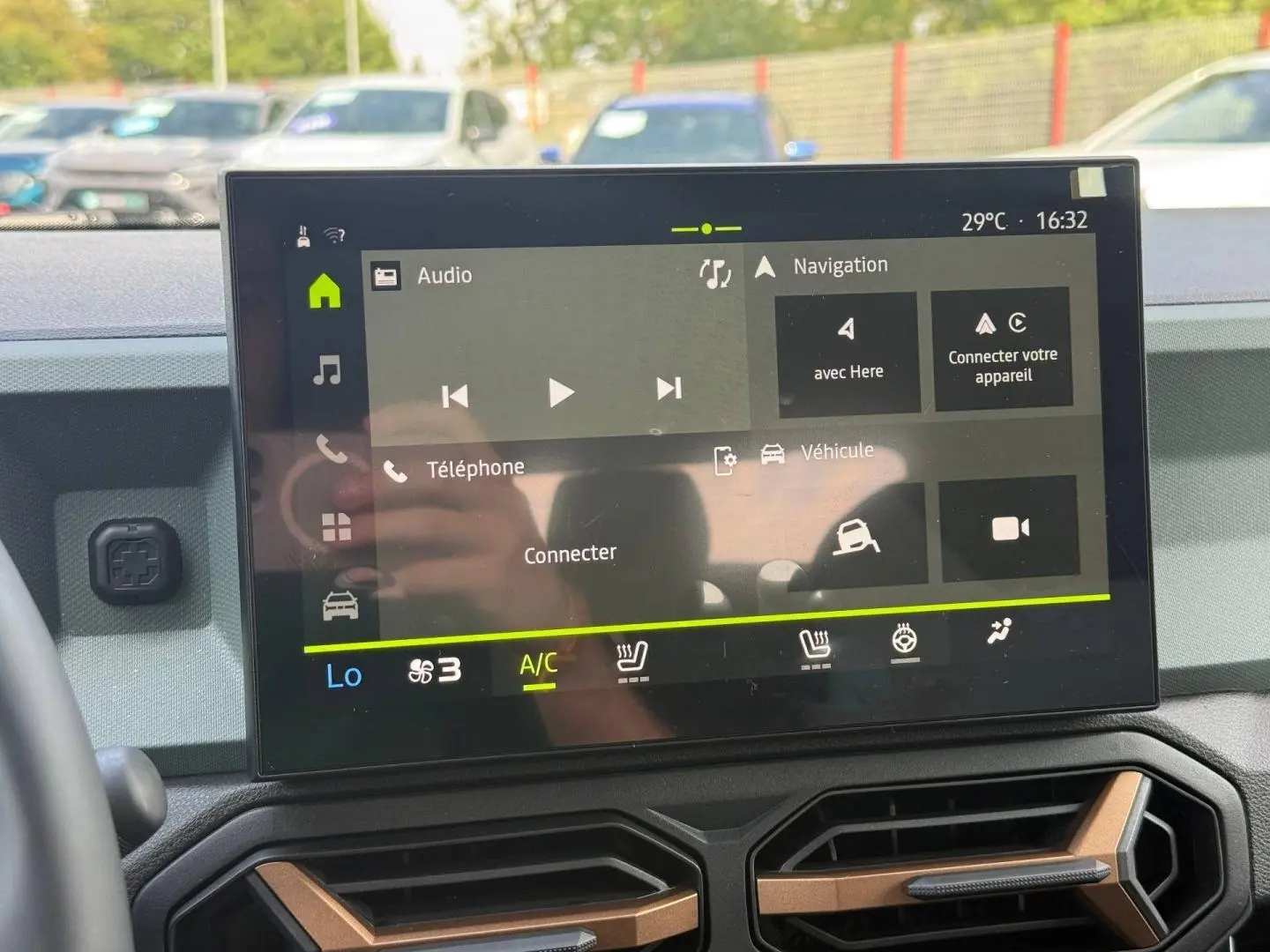 Écran tactile central du tableau de bord du Dacia Duster 2026, avec commandes clim et multimédia visibles.