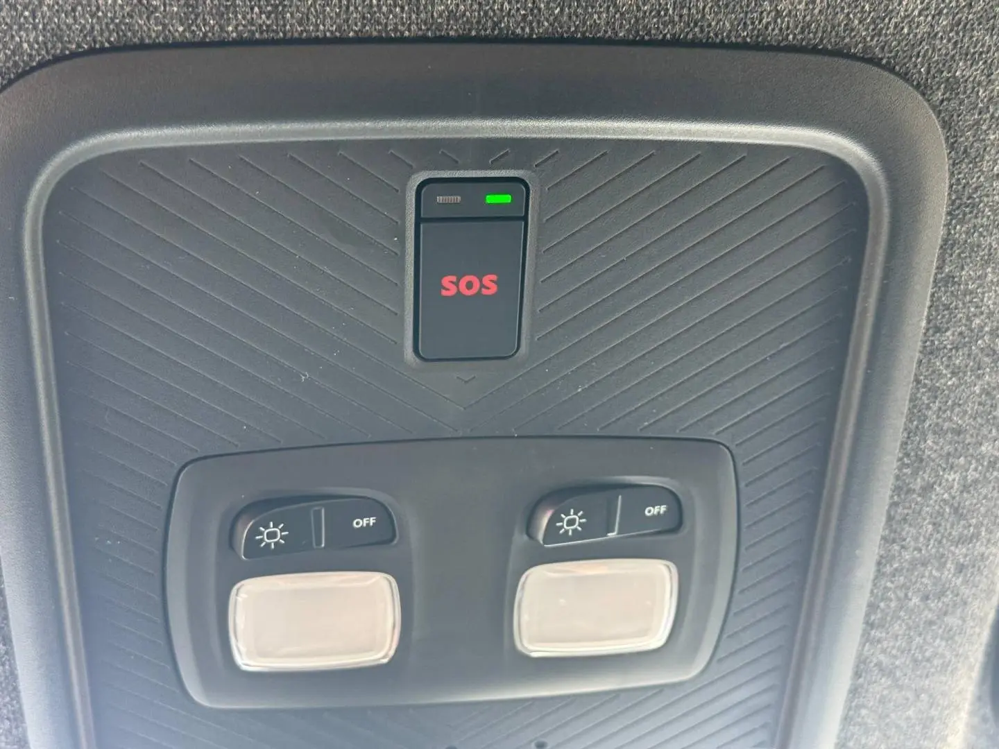 Vue rapprochée du plafonnier intérieur noir avec boutons d’éclairage et bouton SOS rouge du Dacia Duster 2026.