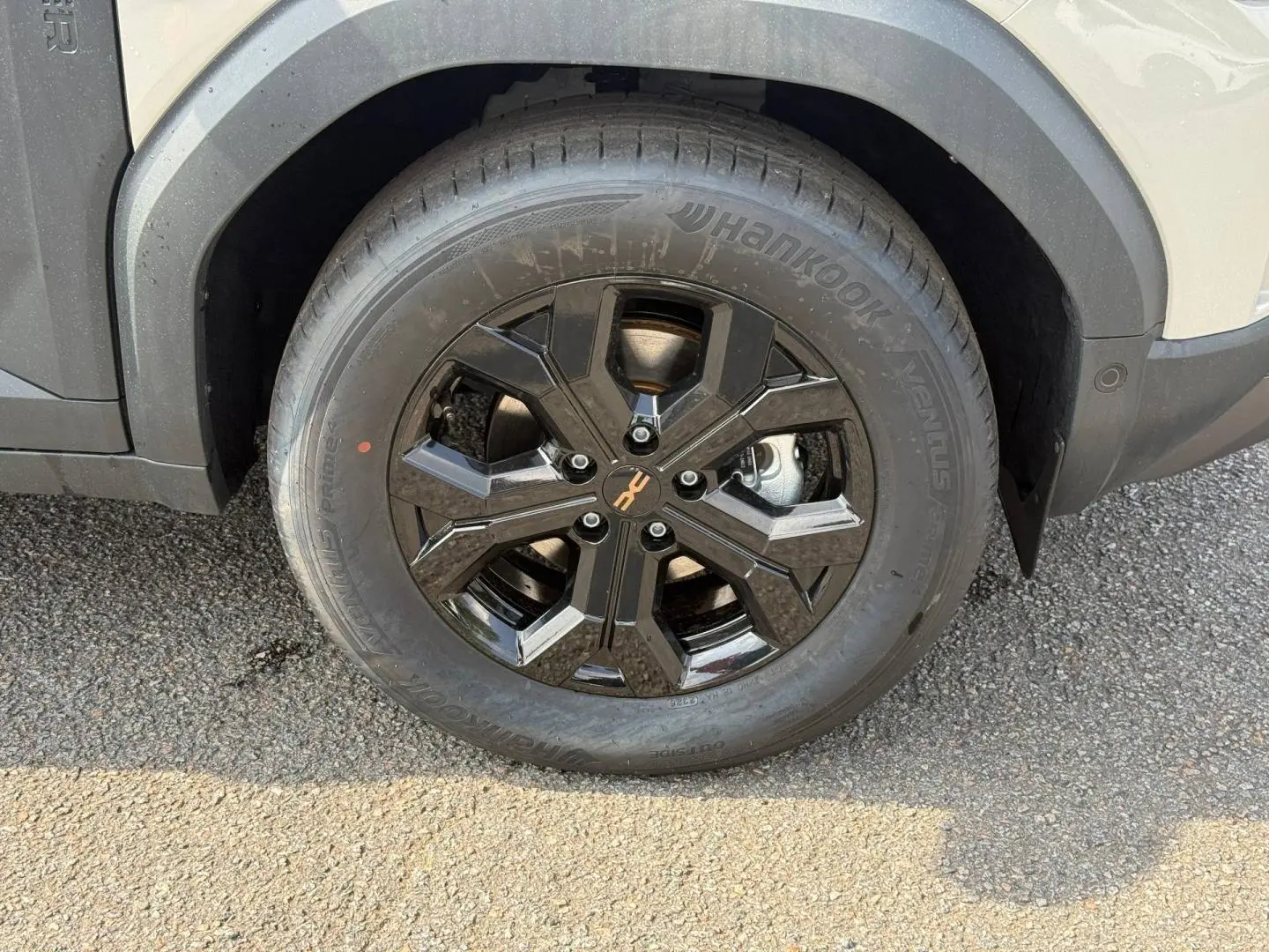 Gros plan sur la jante noire brillante et le pneu Hankook du Dacia Duster blanc côté avant droit.