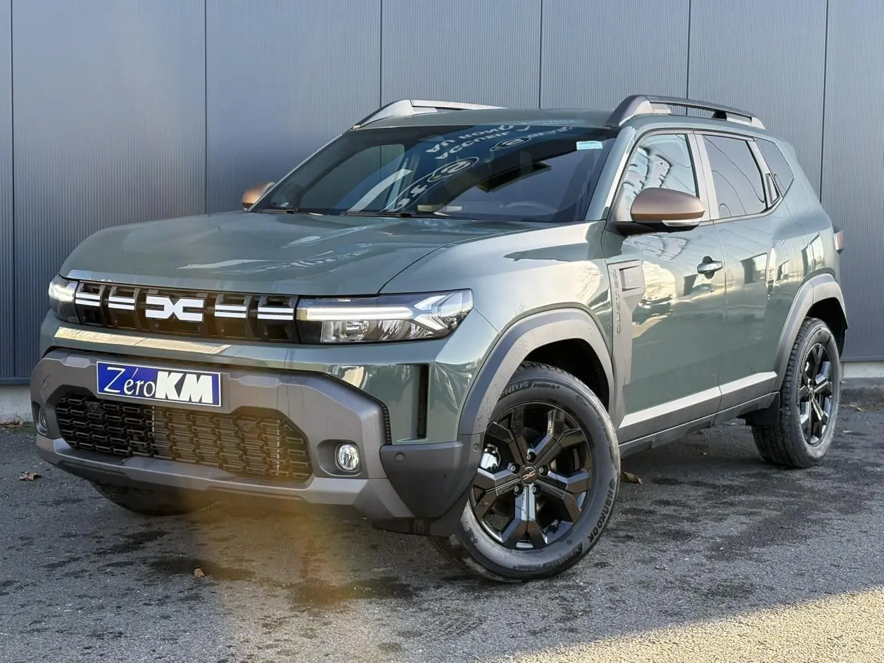 SUV Dacia Duster ECO-G 120 Auto Extrême kaki lichen en 3/4 avant droit avec jantes alliage noires et barres de toit.