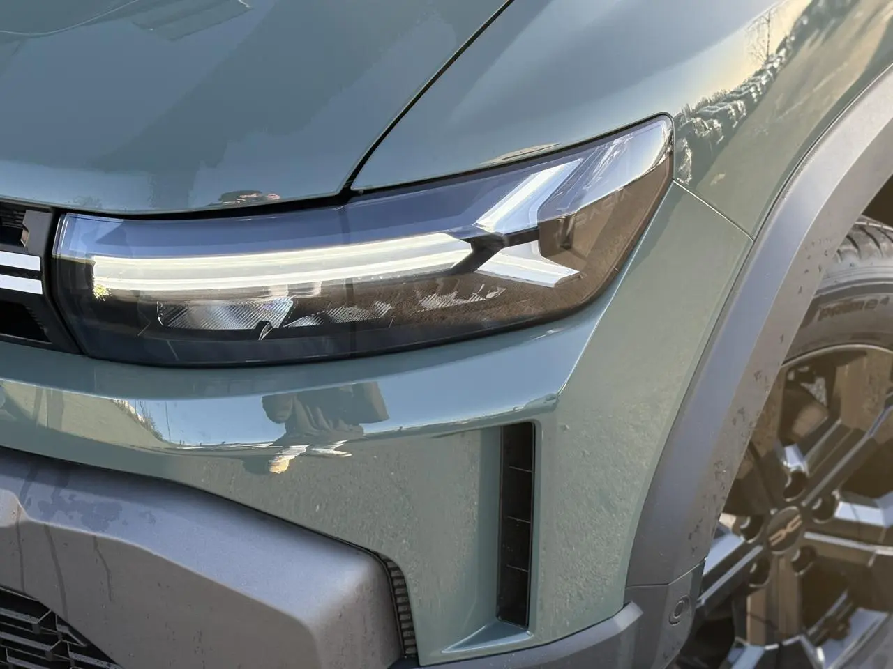Gros plan sur le phare avant droit du Dacia Duster 2026 kaki lichen avec jante alliage noire et signature lumineuse LED.