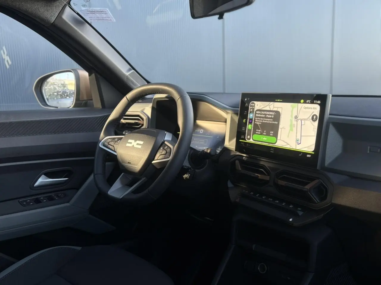 Vue intérieure côté conducteur du Dacia Duster 2026, avec tableau de bord digital et écran tactile central affichant la navigation.