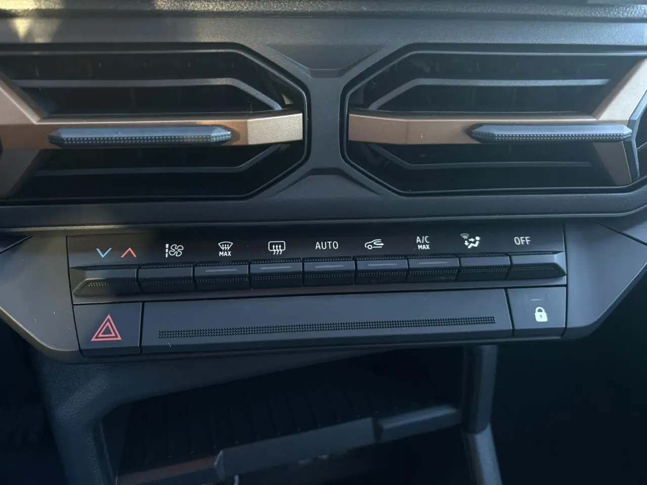 Vue rapprochée de la console centrale du Dacia Duster 2026, boutons de climatisation et aérateurs noirs avec inserts kaki.