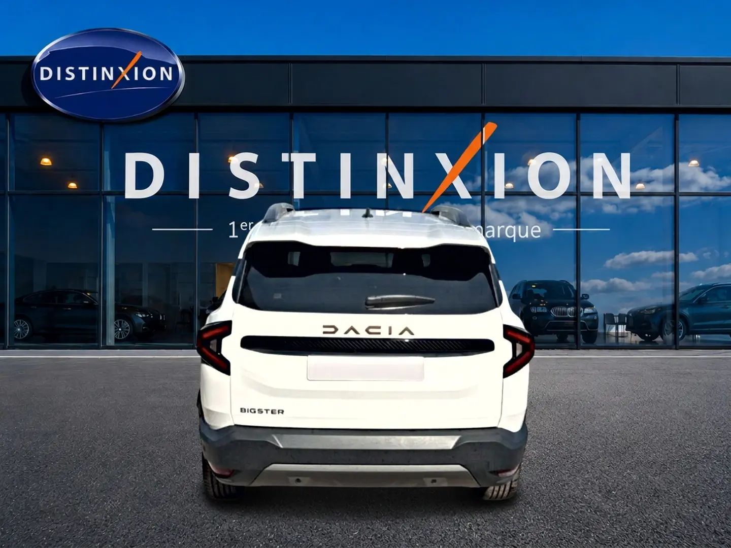 Vue arrière d'un Dacia Bigster blanc 2026 avec logo distinctif et feux arrière en forme de C, devant une vitrine Distinxion.