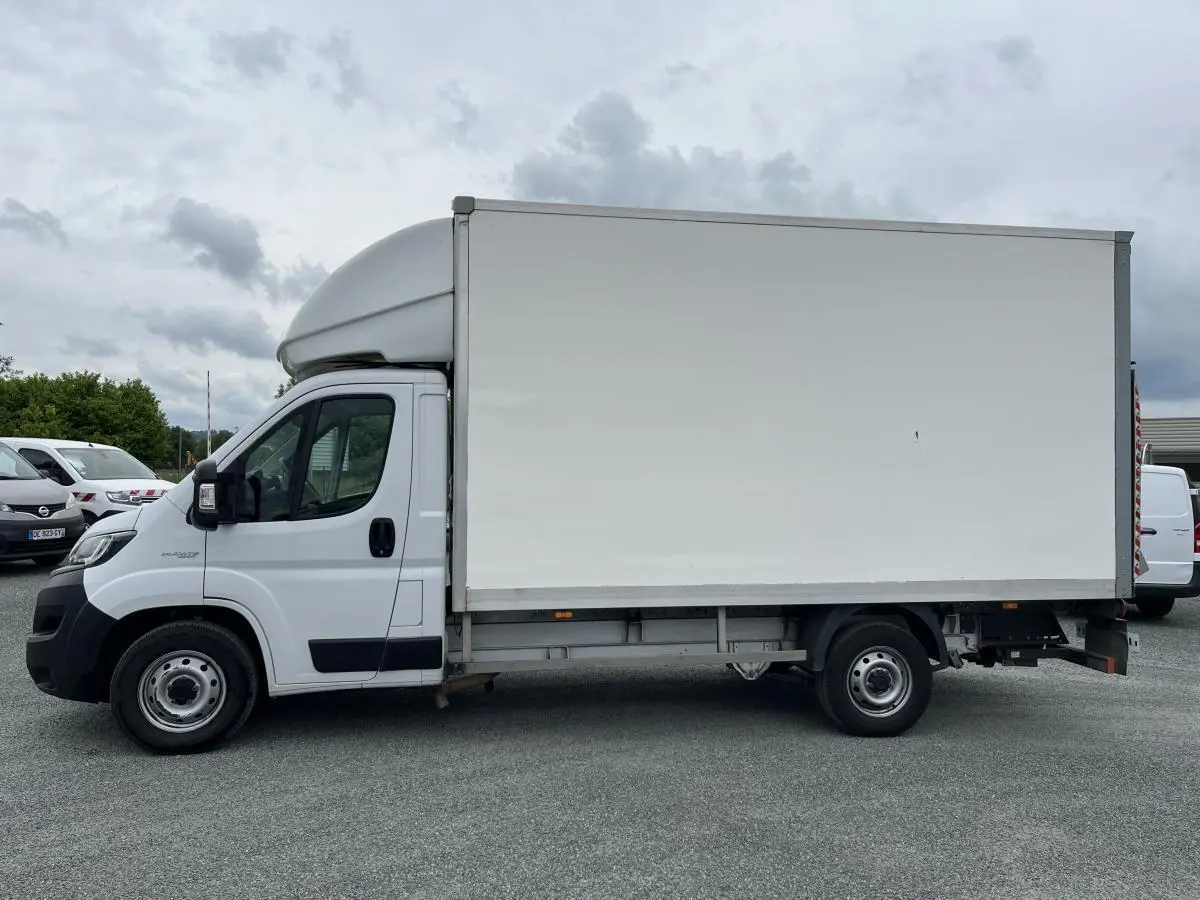 Fourgon FIAT Ducato Maxi Business blanc vu de profil côté gauche avec grande caisse de chargement fermée.