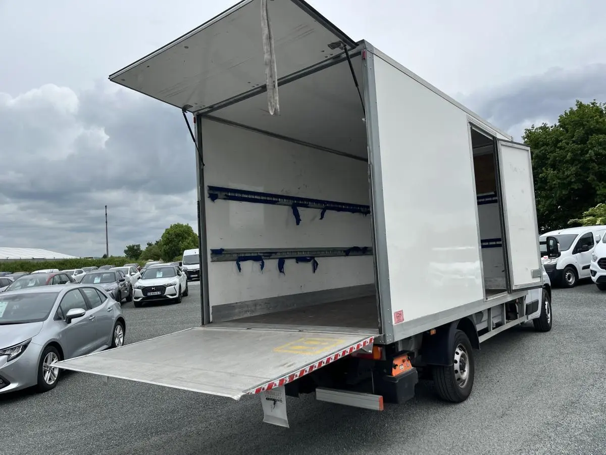 Fiat Ducato Maxi Business blanc vu 3/4 arrière droit avec porte latérale et hayon de chargement ouverts.