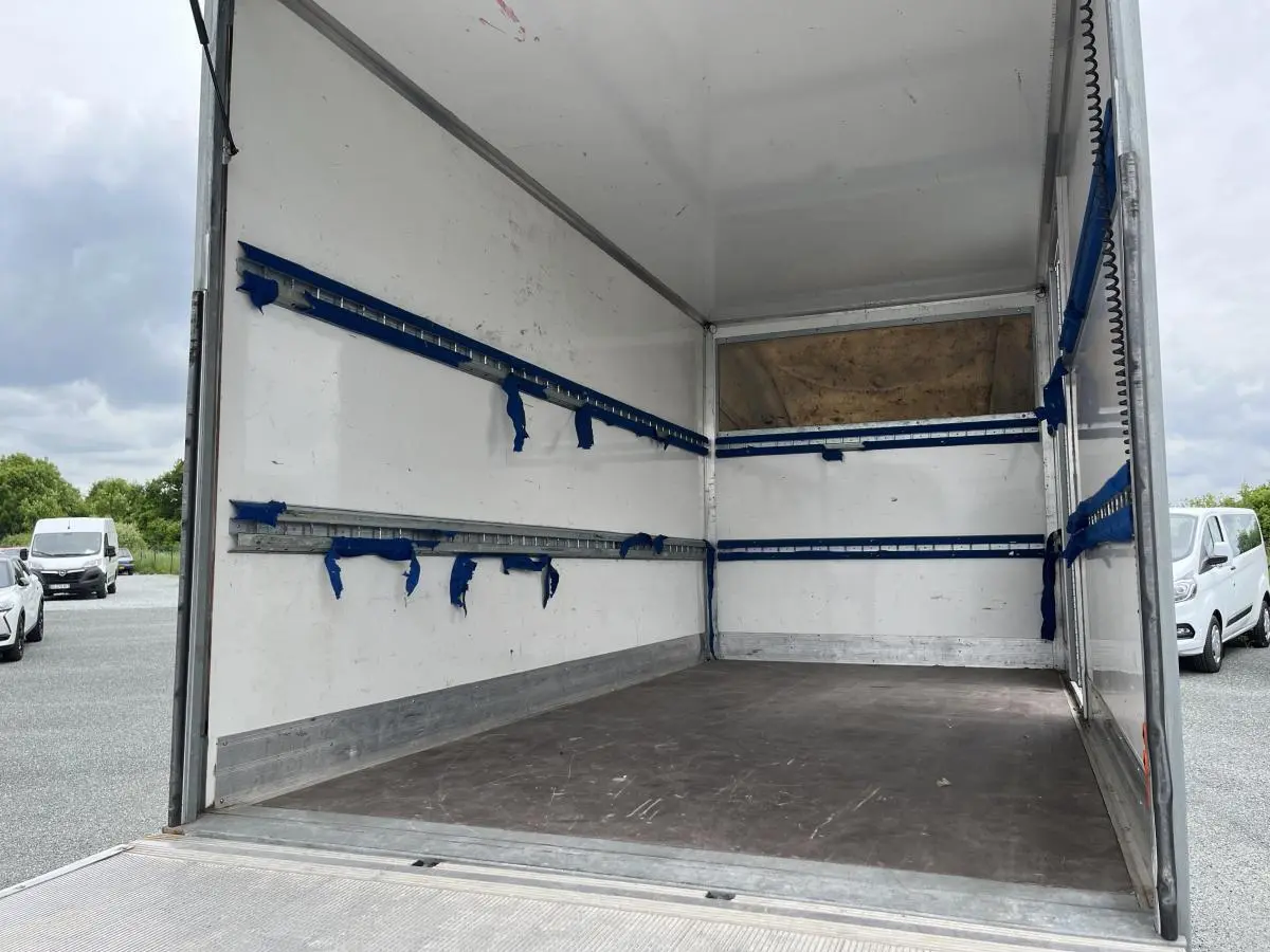 Intérieur du fourgon blanc FIAT Ducato Maxi Business 3.5 vu de l'arrière, montrant l'espace de chargement vide et ses rails bleus.