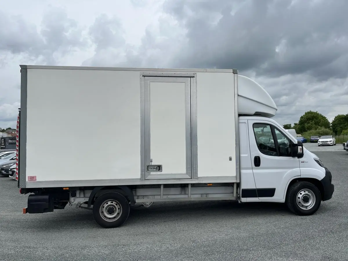 Fiat Ducato Fourgon Maxi Business blanc vu de profil côté gauche avec grande caisse de chargement et porte latérale.