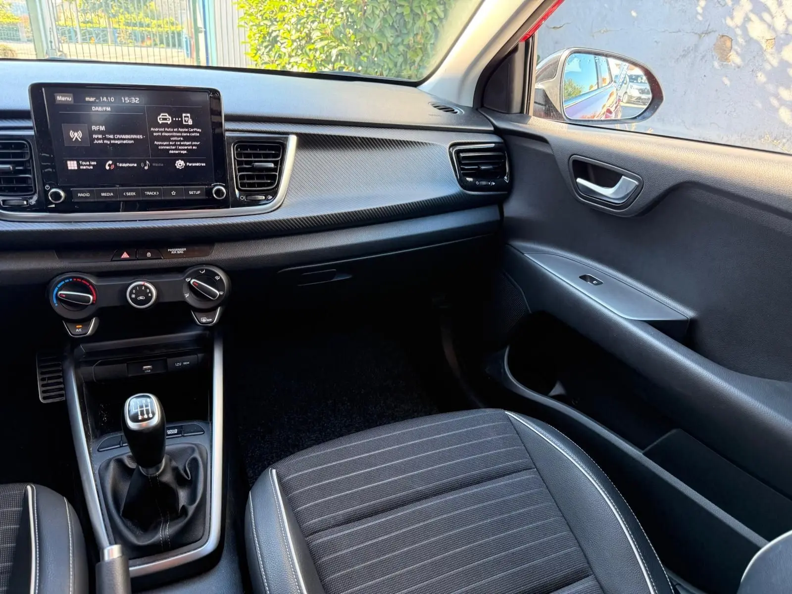Intérieur côté passager de la Kia Rio 2022, montrant la console centrale avec boîte manuelle et tableau de bord noir.