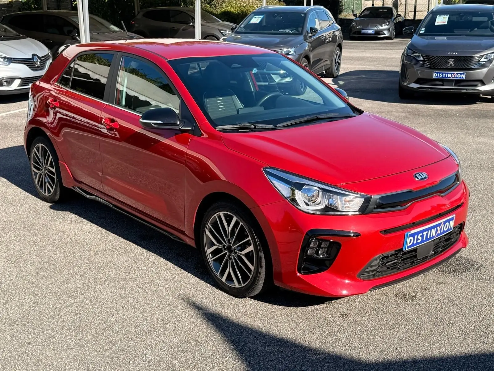 KIA RIO 2022 rouge grenadine vue 3/4 avant droit, avec jantes alliage et calandre noire GT-Line distincte.