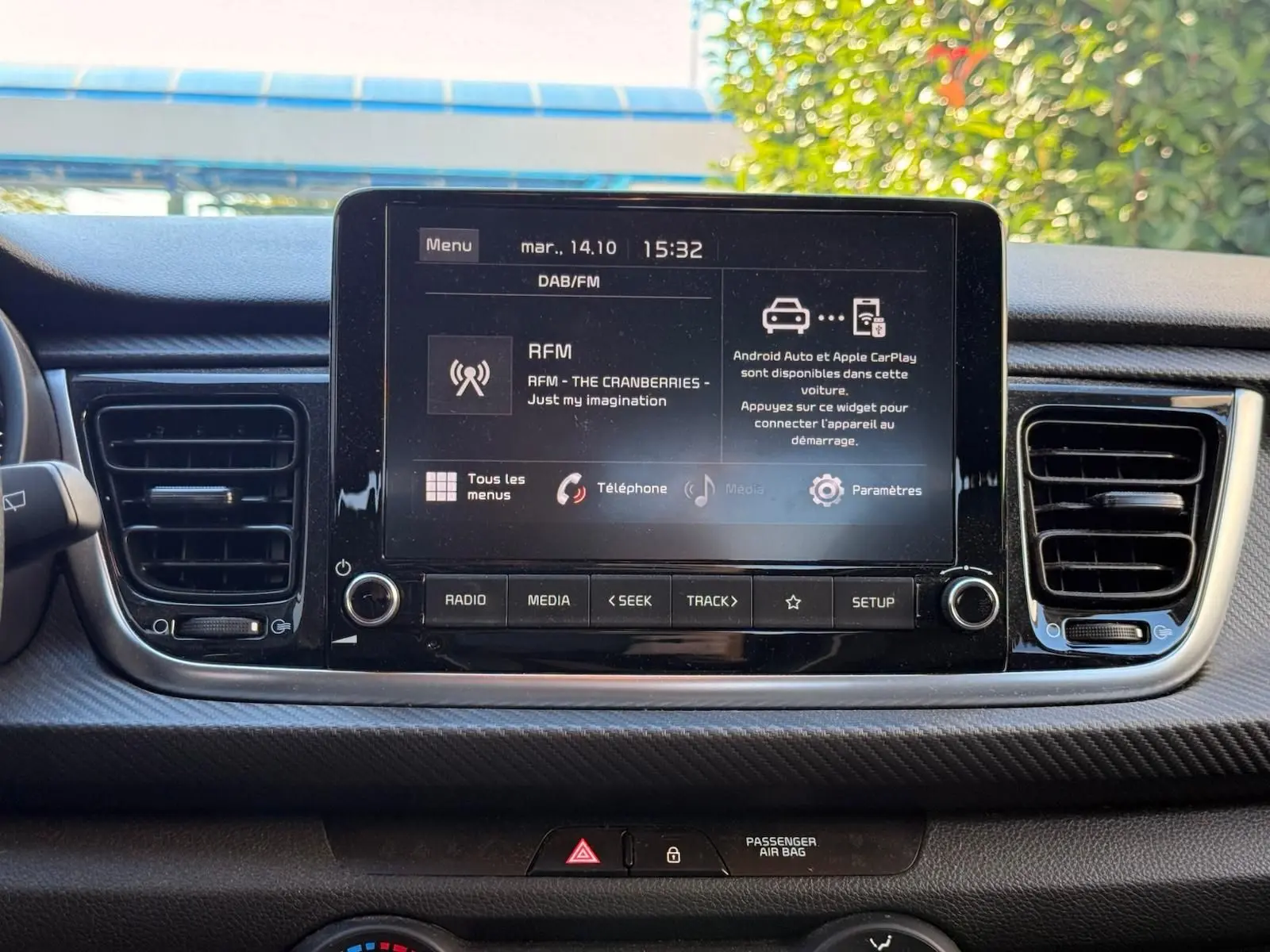 Écran tactile central de la Kia Rio 2022 affichant les options multimédia, entouré des aérateurs et commandes du tableau de bord.