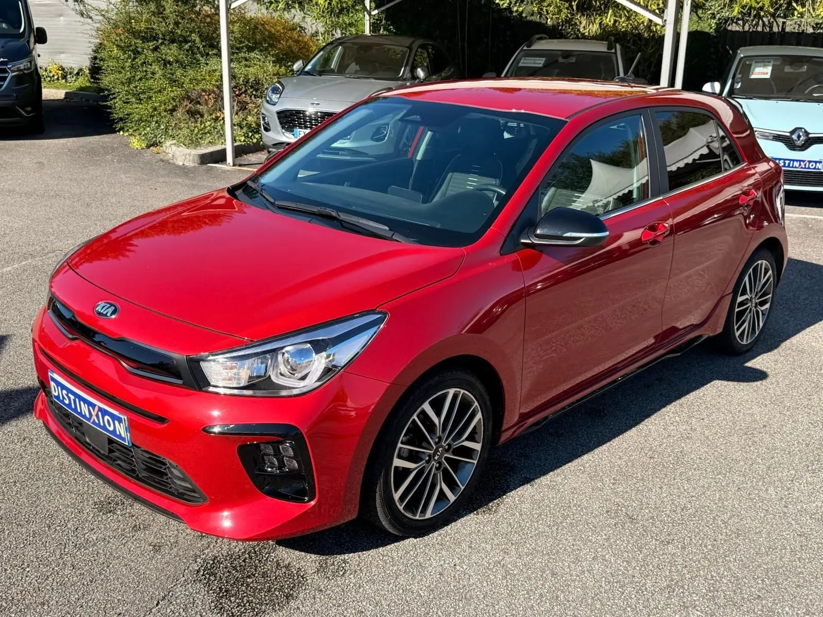 KIA RIO rouge grenadine vue 3/4 avant droit, avec jantes alliage et rétroviseurs noirs brillants.