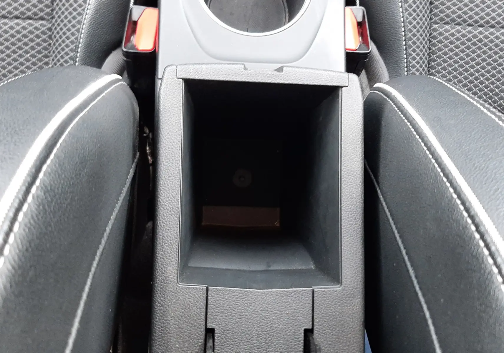 Vue plongeante sur la console centrale noire avec porte-gobelet et rangement ouvert du Renault Arkana Intens 2021.