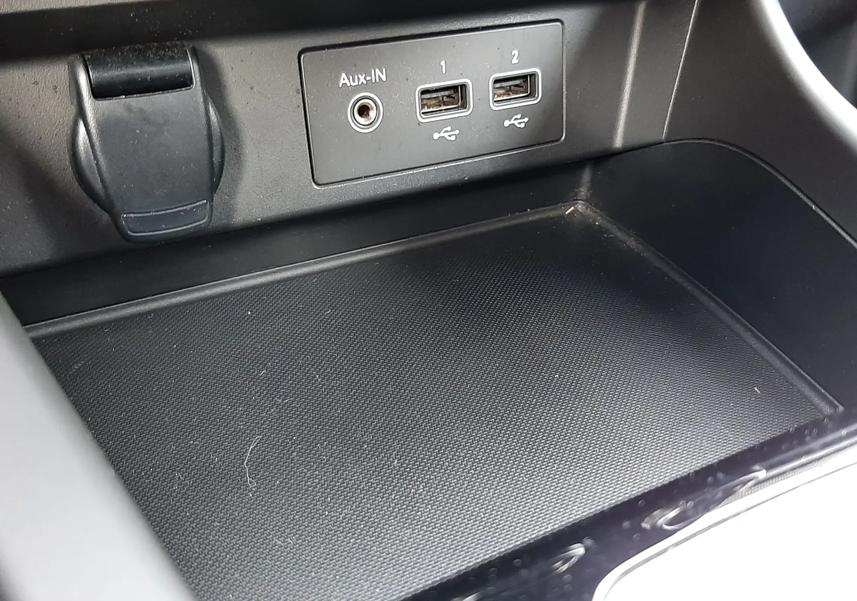 Gros plan sur la console centrale noire du Renault Arkana 1.6 E-TECH 145 Intens avec prises USB et Aux-In visibles.