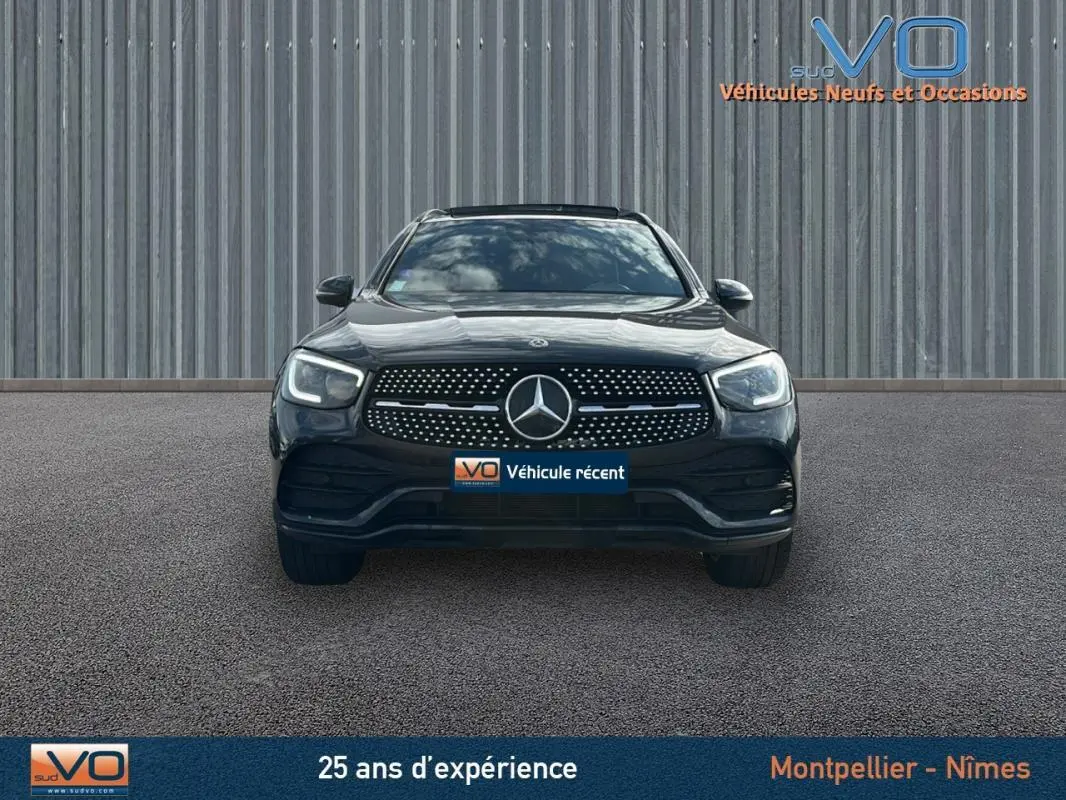 Vue frontale d'un Mercedes GLC 300 de 2020 gris anthracite avec calandre AMG et phares LED allumés.