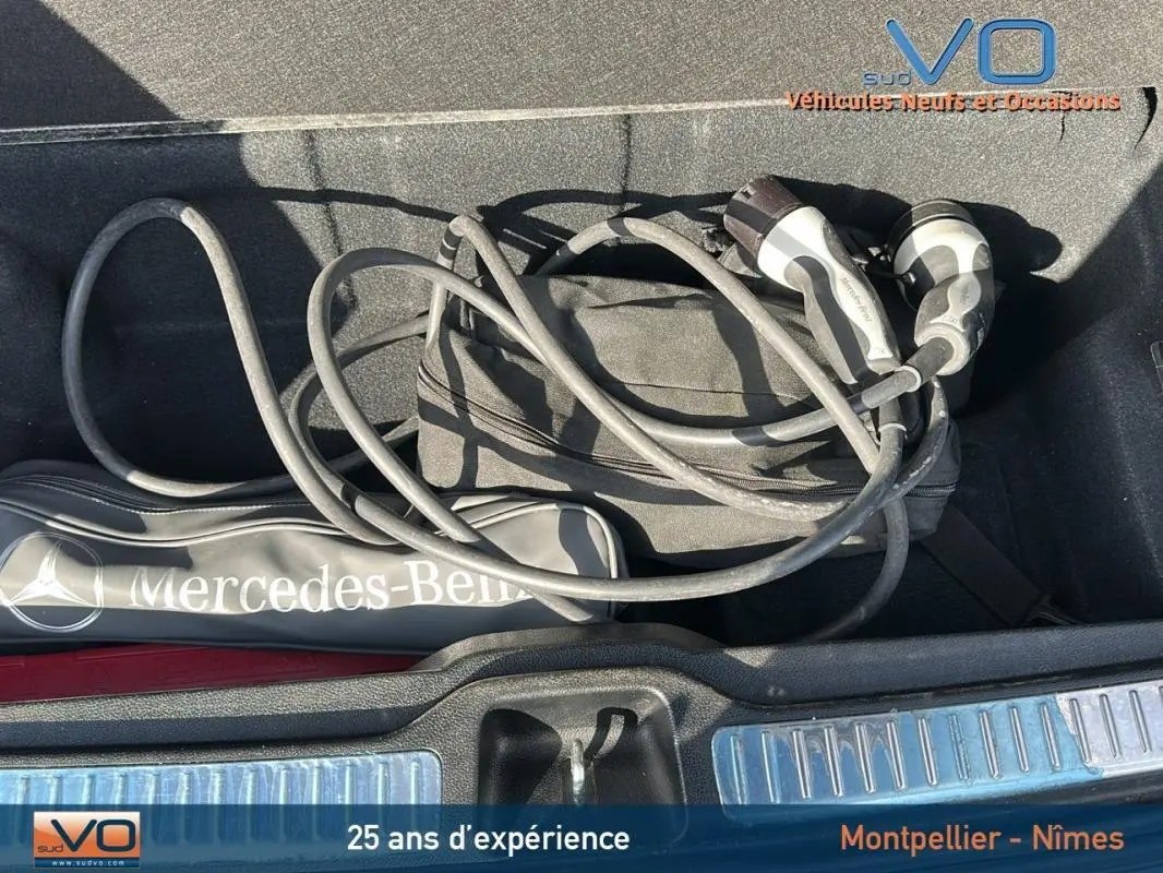 Vue plongeante sur le coffre d'un Mercedes GLC 300 de 2020 avec câble de recharge et sac de marque gris anthracite.
