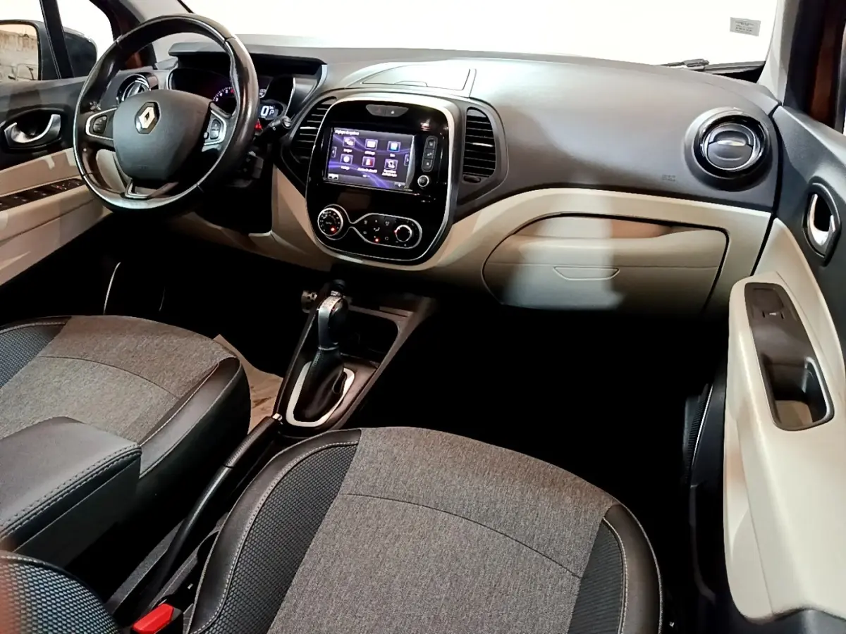 Intérieur beige et noir du Renault Captur Intens 2019, vue de profil côté conducteur avec tableau de bord et écran tactile.