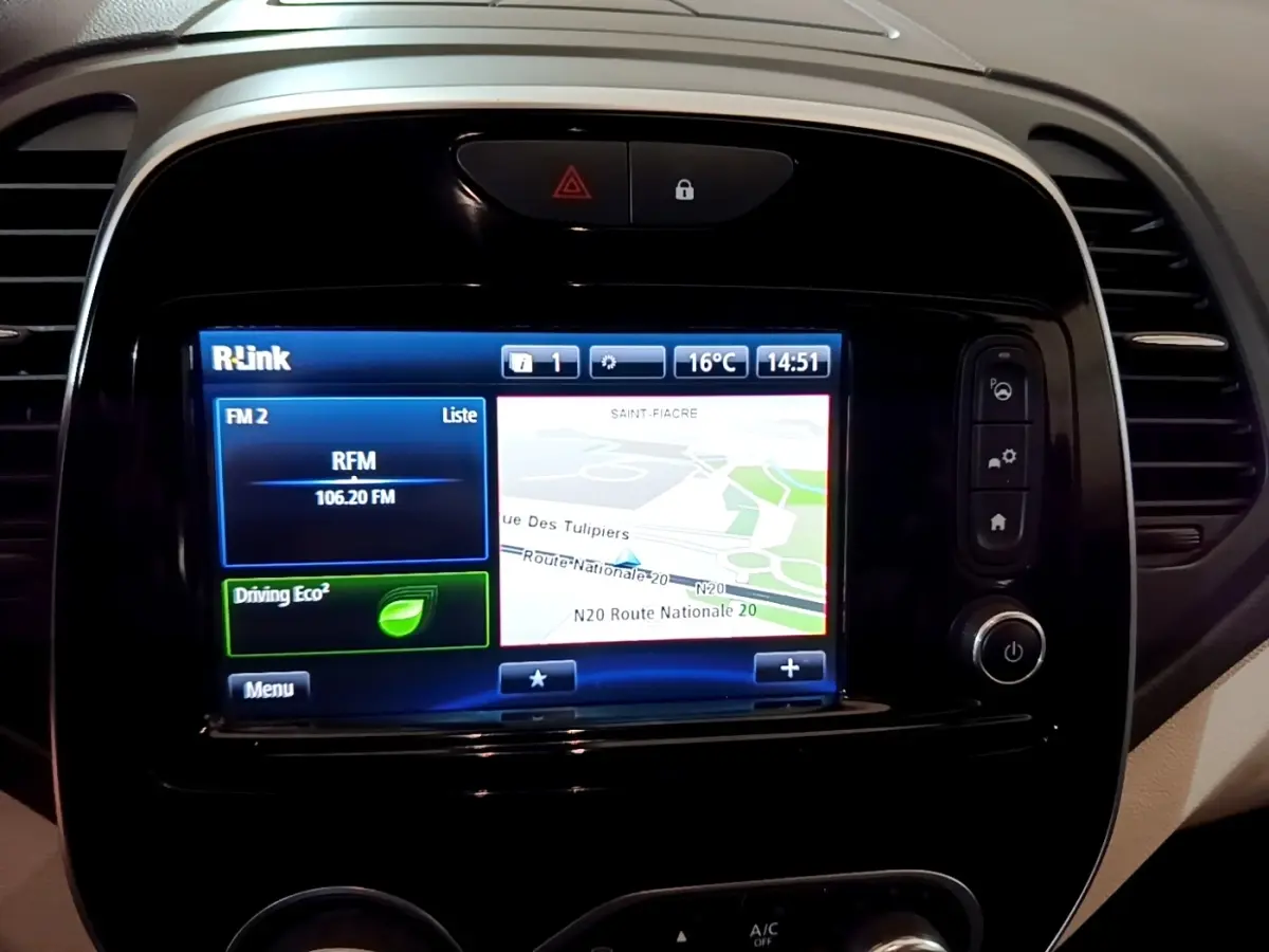 Gros plan sur l'écran tactile central du tableau de bord du Renault Captur Intens orange, affichant la navigation et la radio FM.