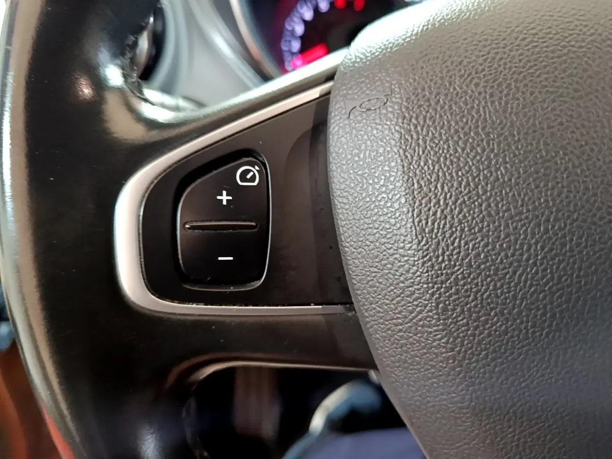 Gros plan sur les commandes de régulateur de vitesse au volant cuir du Renault Captur Intens orange 2019.