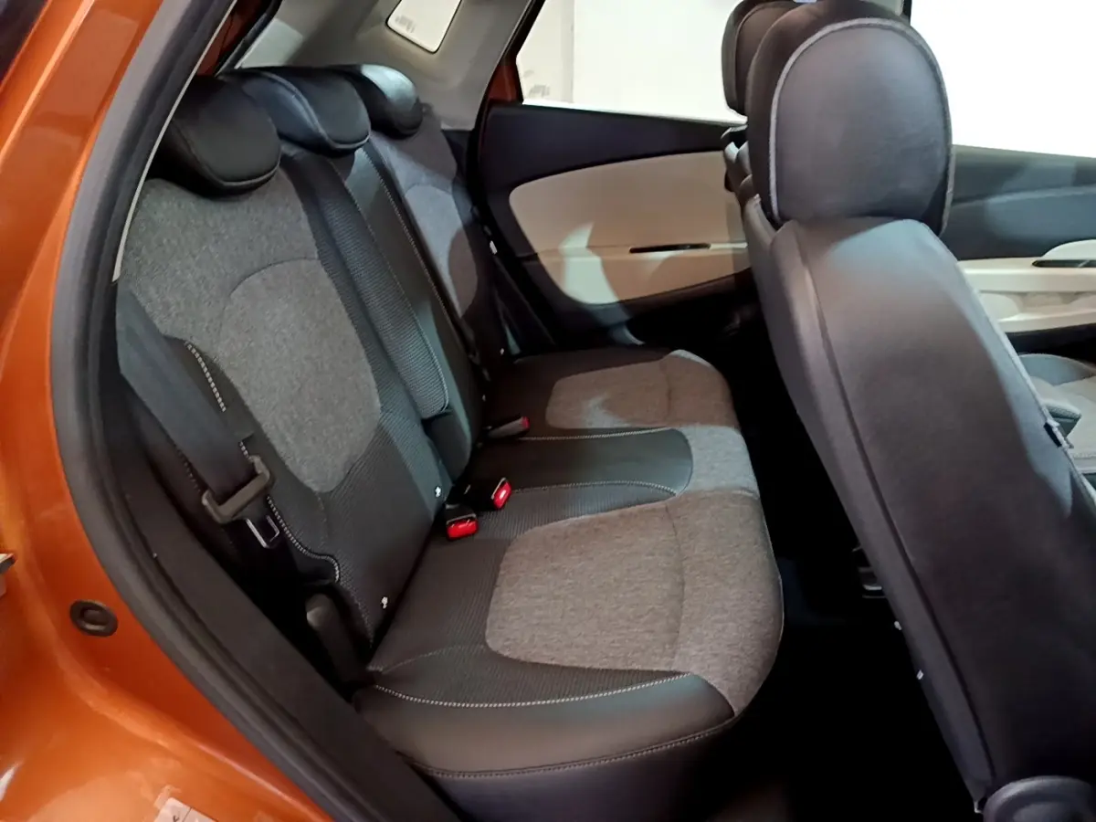 Vue intérieure du côté arrière gauche du Renault Captur Intens orange, montrant la banquette arrière en tissu gris et noir.