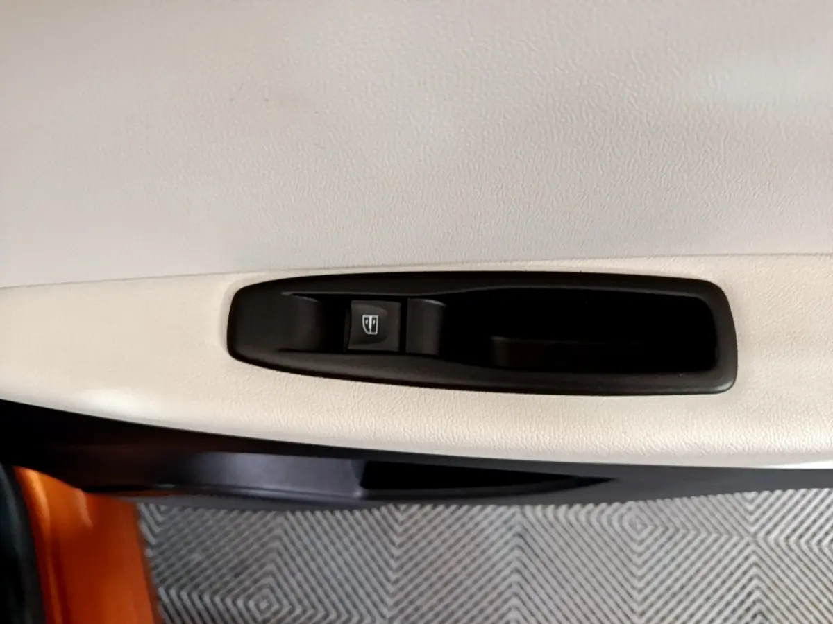 Bouton de commande de lève-vitre sur la porte intérieure beige côté conducteur d'un Renault Captur orange 2019.