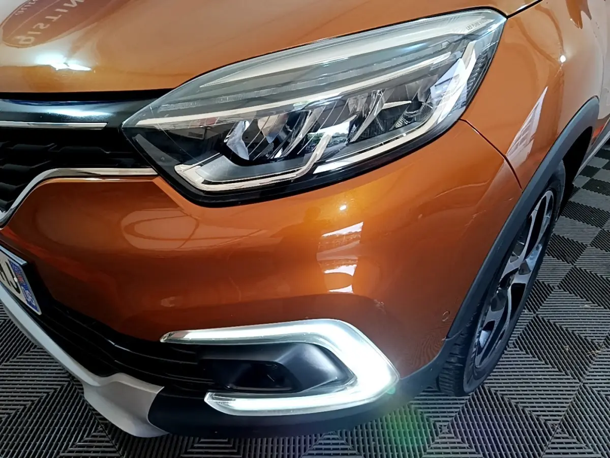 Gros plan sur l'avant droit orange du Renault Captur 2019, mettant en valeur son phare LED et la signature lumineuse chromée.
