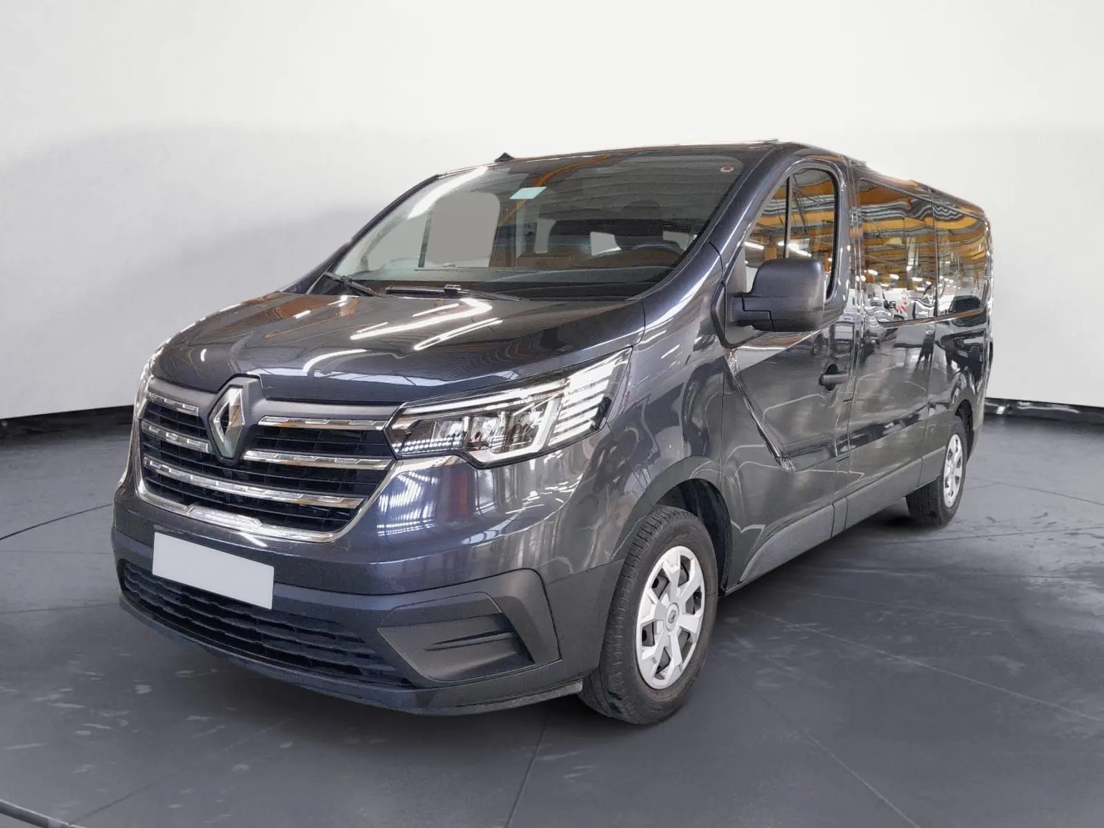 Renault Trafic Combi gris comète en 3/4 avant droit, mettant en valeur sa calandre chromée et ses grandes vitres latérales.