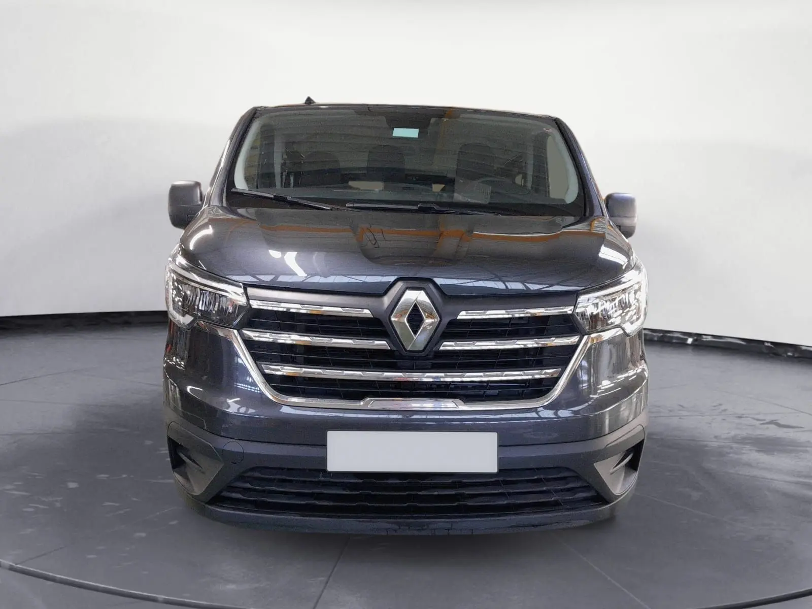 Vue de face d'un Renault Trafic Combi gris comète, mettant en valeur la calandre chromée et les phares modernes.