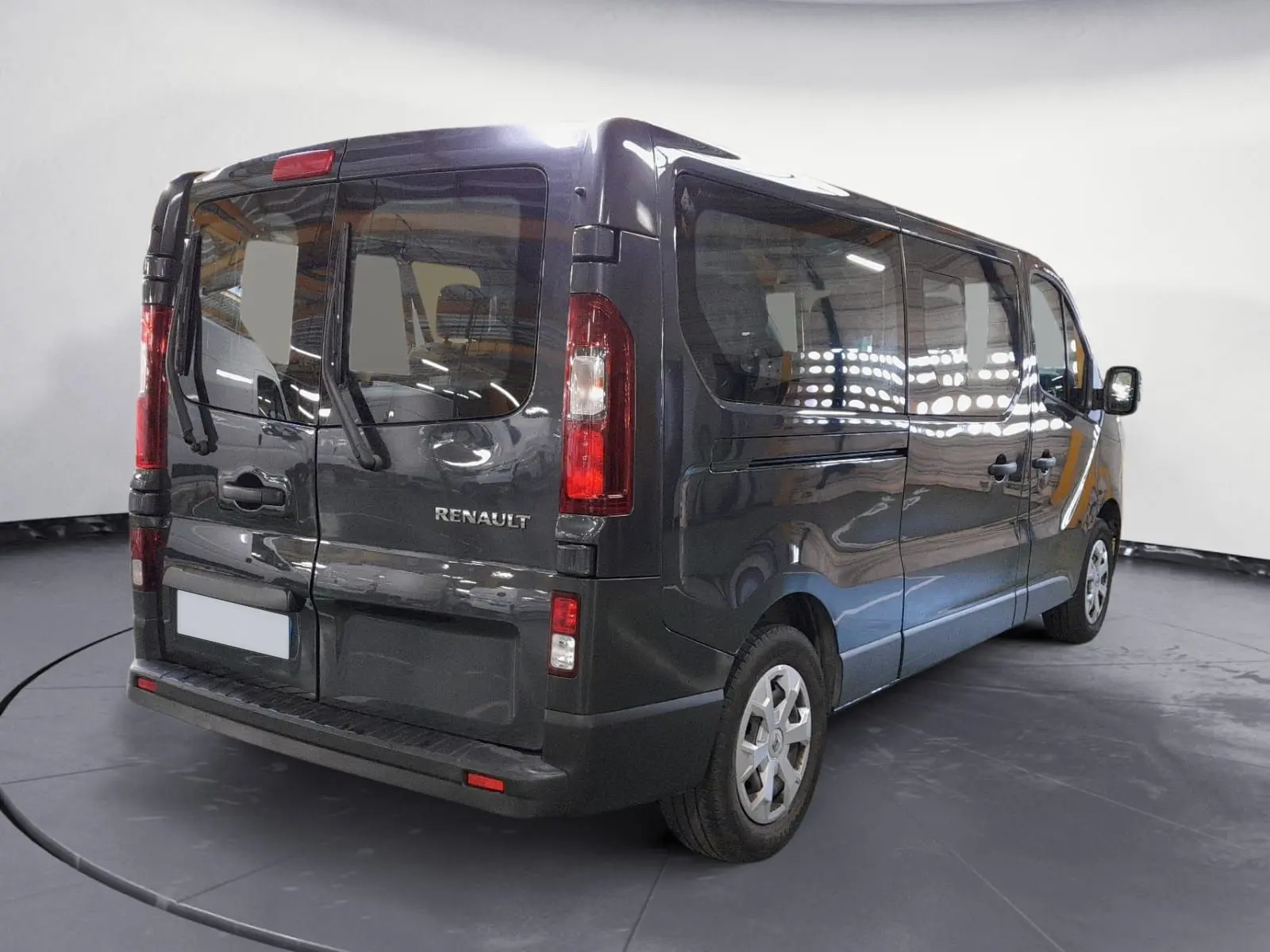 Vue 3/4 arrière droite du Renault Trafic Combi gris comète, mettant en valeur ses grandes vitres latérales et portes arrière battantes.