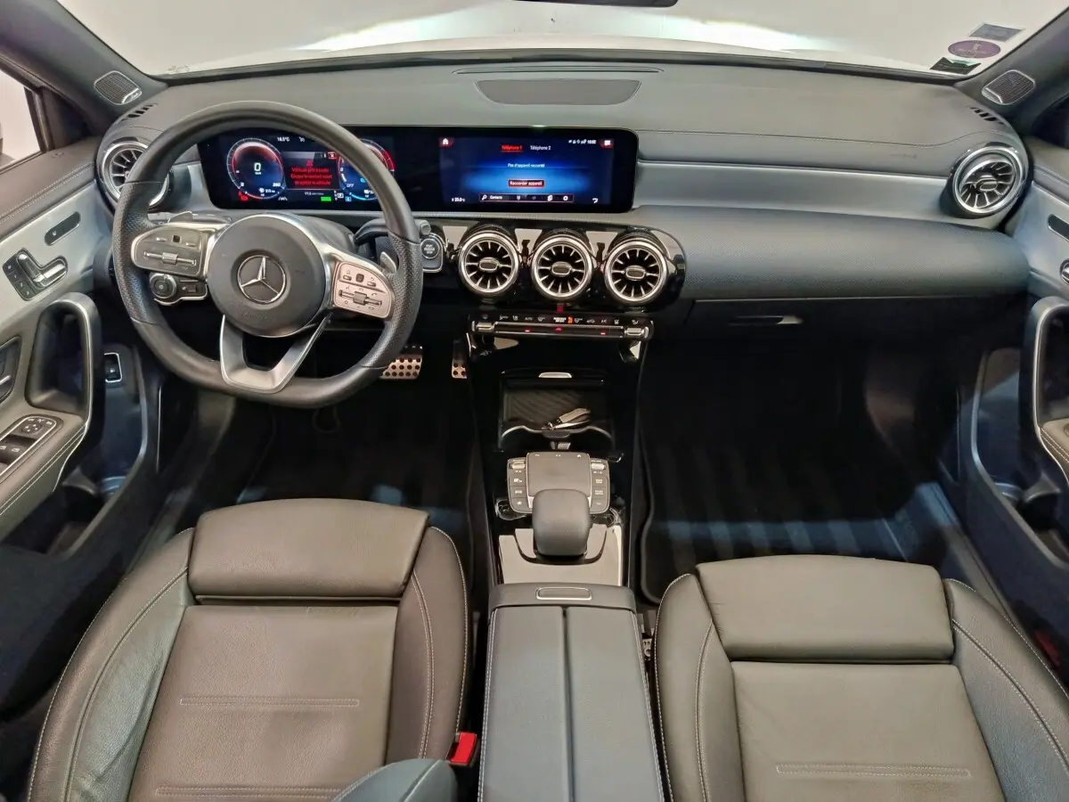 Vue intérieure avant de la Mercedes Classe A A 250 e AMG Line 2021, tableau de bord noir avec écran tactile et volant cuir alu multifonctions.