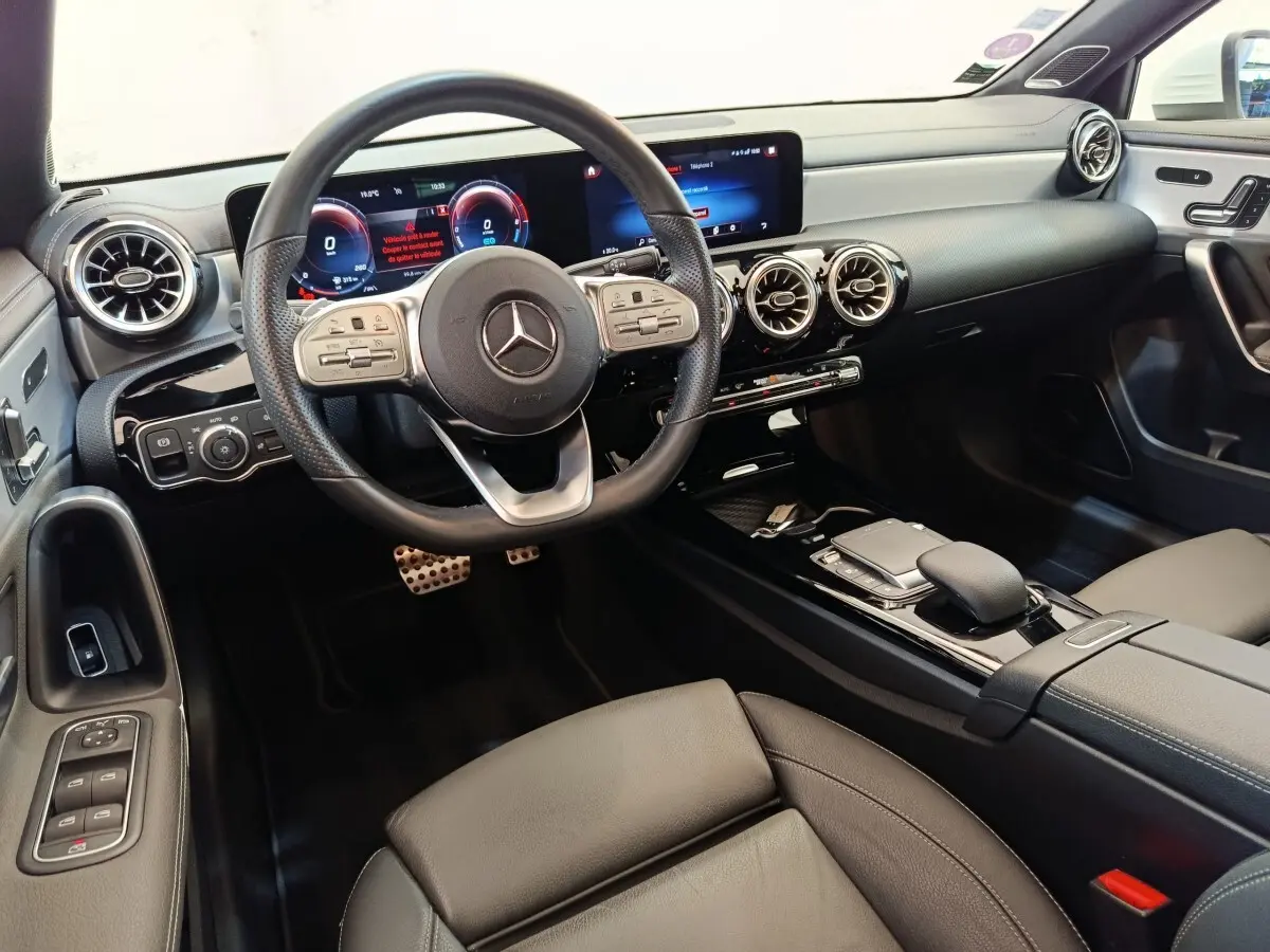 Intérieur de la Mercedes Classe A 250 e AMG Line 2021, vue avant centrée sur le volant cuir alu et tableau de bord numérique.