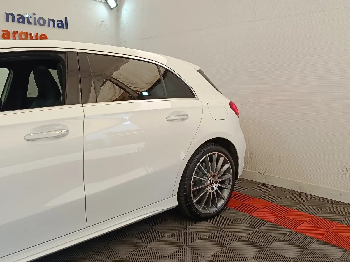 Vue latérale arrière droite d'une Mercedes Classe A blanche avec jantes AMG et rétroviseurs rabattables électriquement.