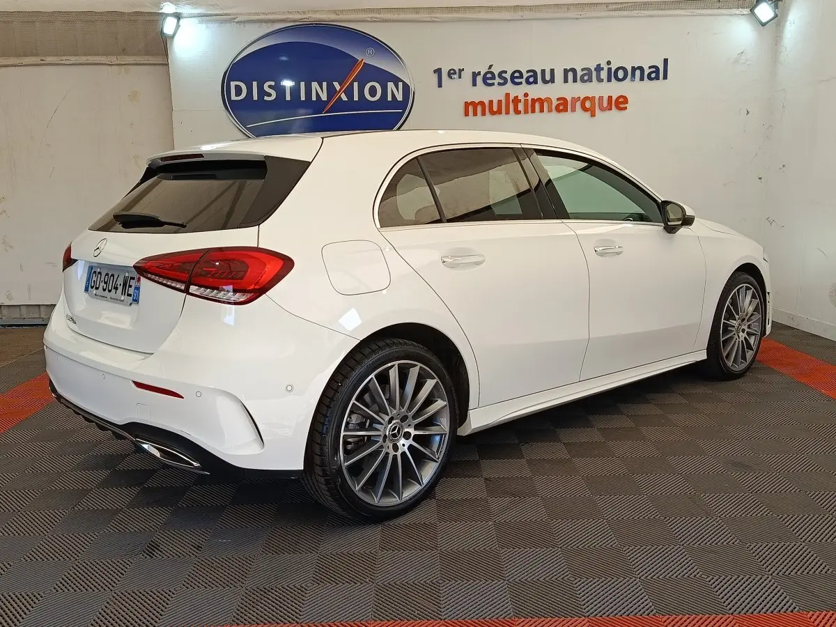 Vue 3/4 arrière droite d'une Mercedes Classe A blanche A 250 e AMG Line avec jantes alliage et vitres teintées.
