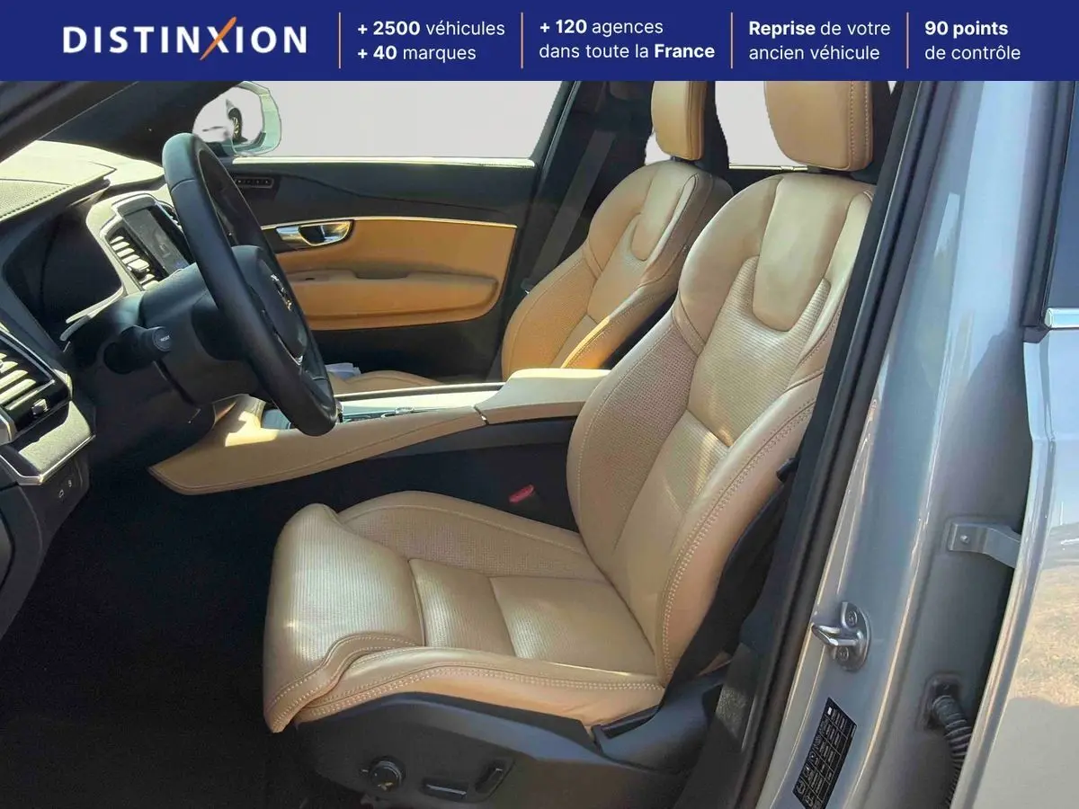 Vue intérieure côté conducteur du Volvo XC90 gris 2024, mettant en valeur les sièges en cuir beige et le tableau de bord moderne.