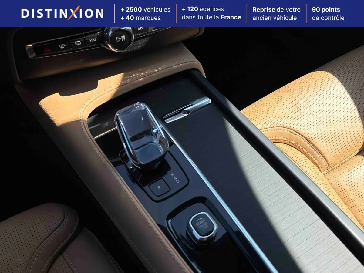 Gros plan sur la console centrale beige du Volvo XC90 2024 avec levier de vitesses cristal et bouton démarrage.