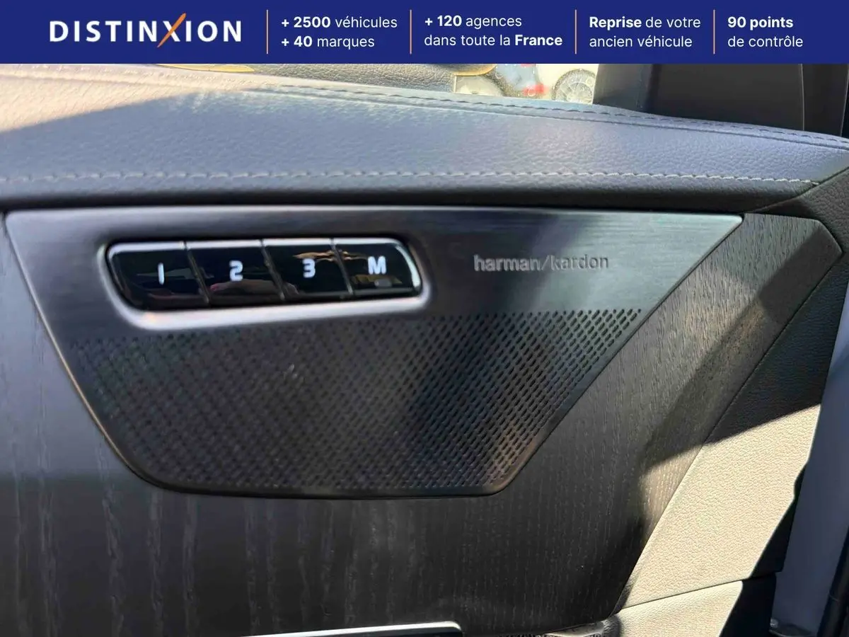 Détail intérieur montrant la porte côté droit avec haut-parleur Harman Kardon et boutons mémoire sur Volvo XC90 gris.