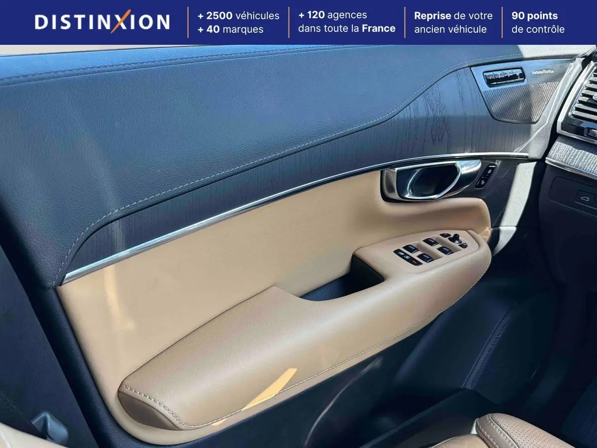 Détail de la porte avant droite intérieure beige et noire du Volvo XC90 2024 avec commandes de vitres et insert carbone.