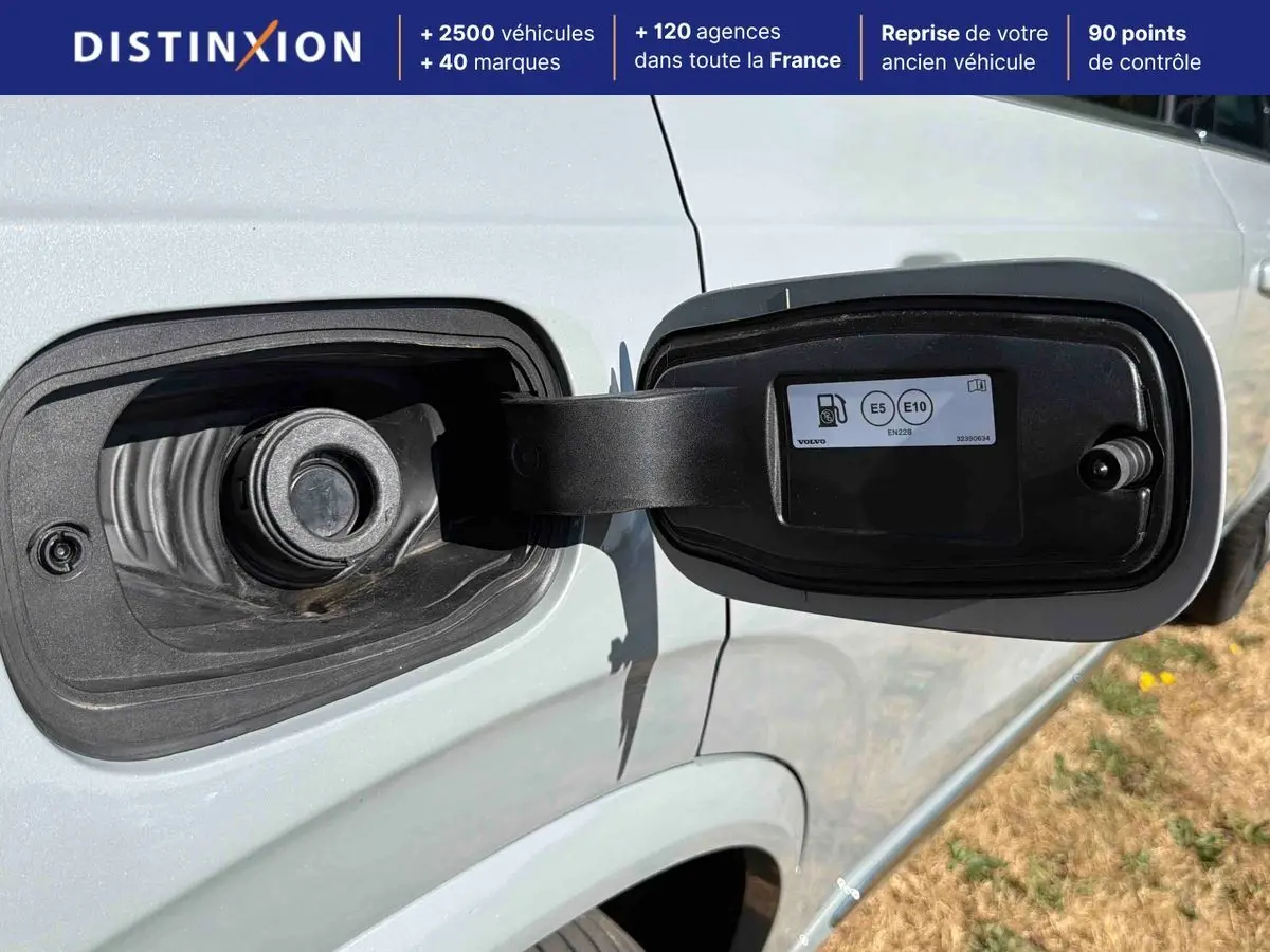 Vue rapprochée du bouchon de réservoir ouvert côté gauche sur un Volvo XC90 gris clair 2024 hybride rechargeable.