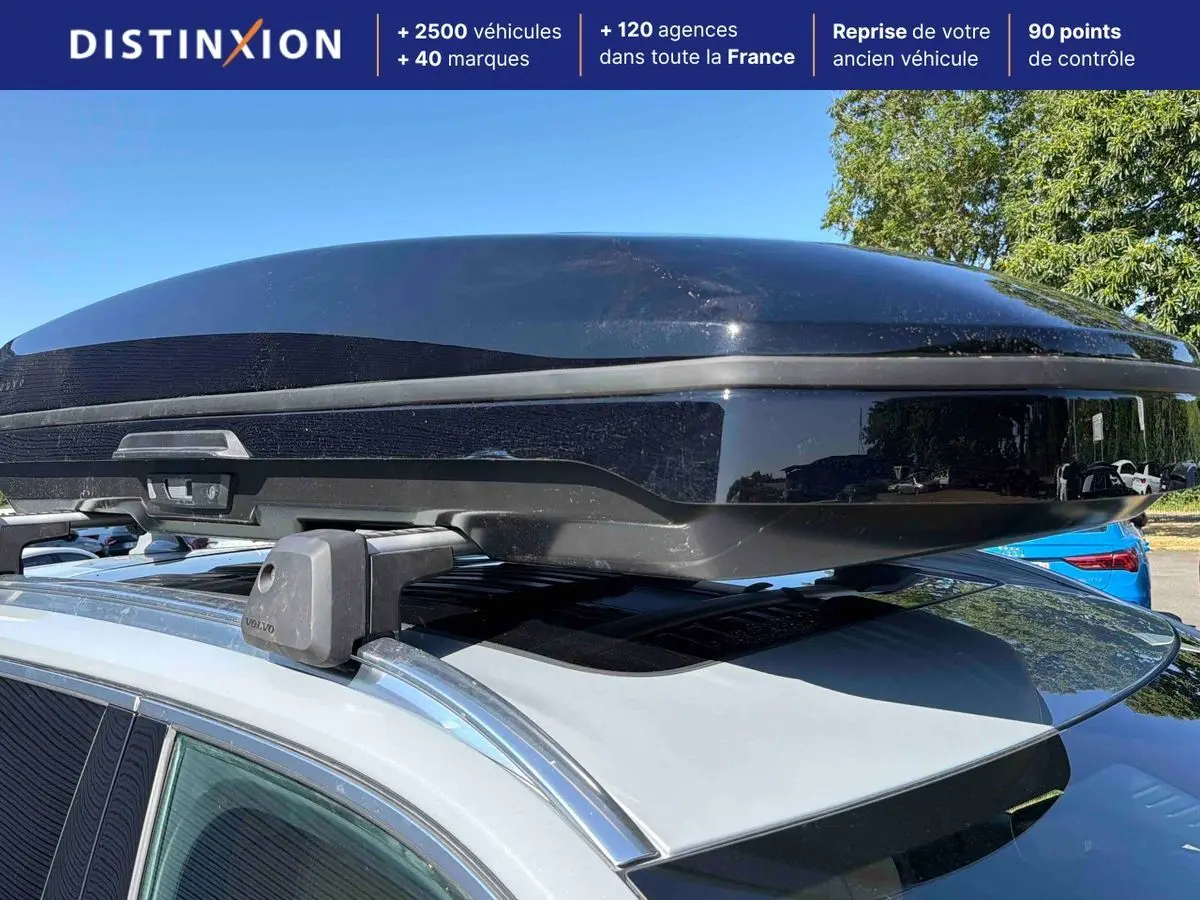 Vue rapprochée du coffre de toit noir sur barres de toit d’un Volvo XC90 gris 2024, côté gauche visible.