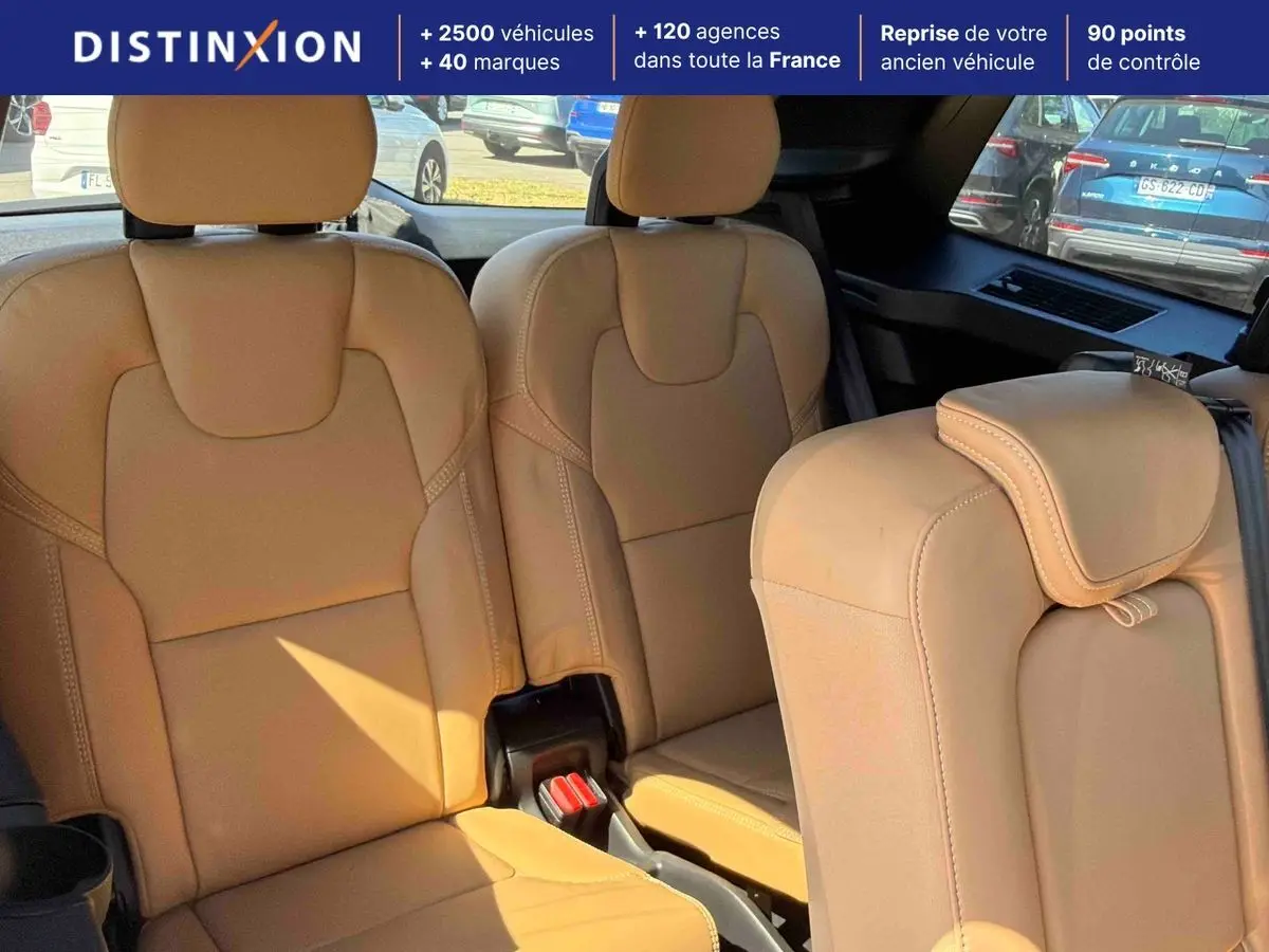 Intérieur montrant la troisième rangée de sièges en cuir beige du Volvo XC90, avec vue arrière et fenêtres teintées.
