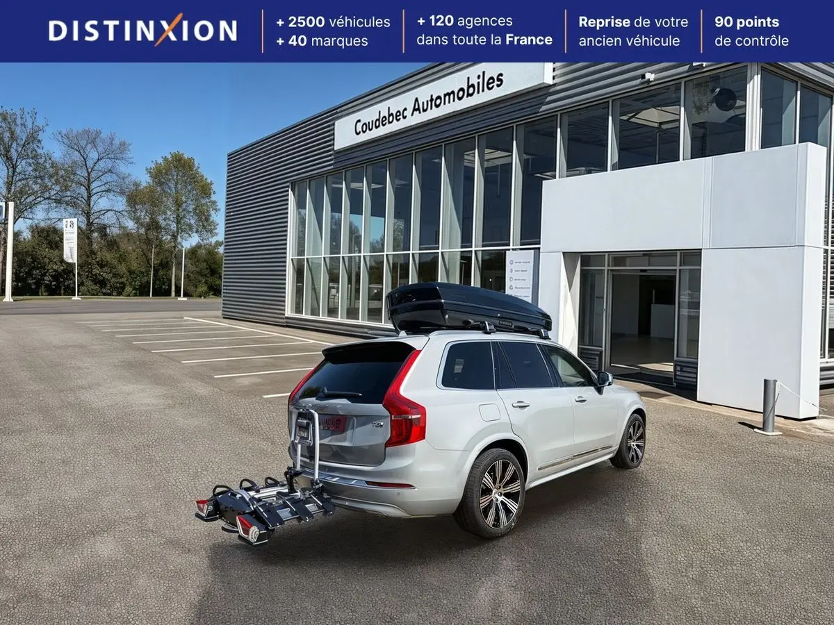 Vue 3/4 arrière droite d’un Volvo XC90 gris avec coffre de toit noir et porte-vélos fixé à l’attelage.