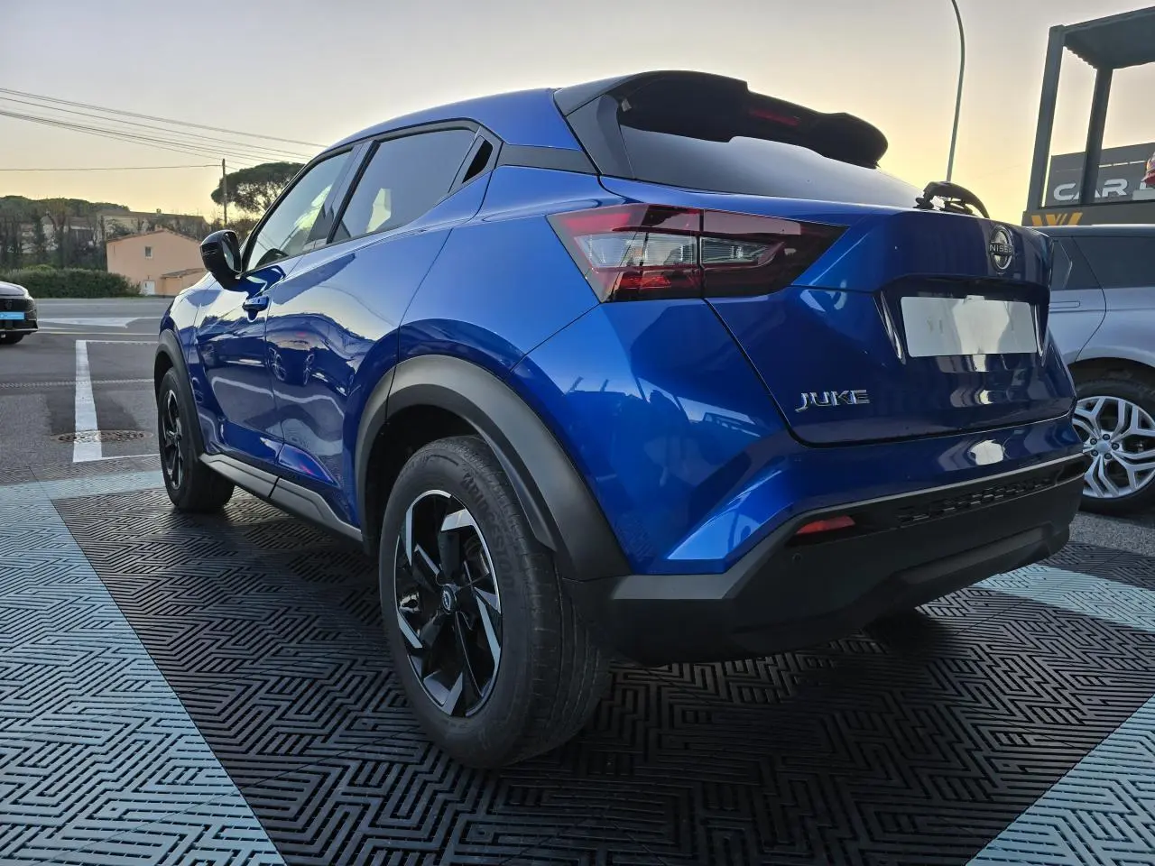 Vue 3/4 arrière droite du Nissan Juke II bleu magnetic avec jantes alliage noires et vitres teintées.