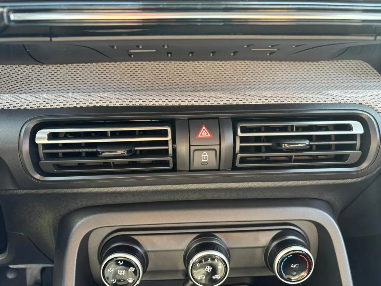 Détail de la console centrale avec aérateurs et commandes de climatisation d'une Citroën C3 Rouge Elixir toit noir.