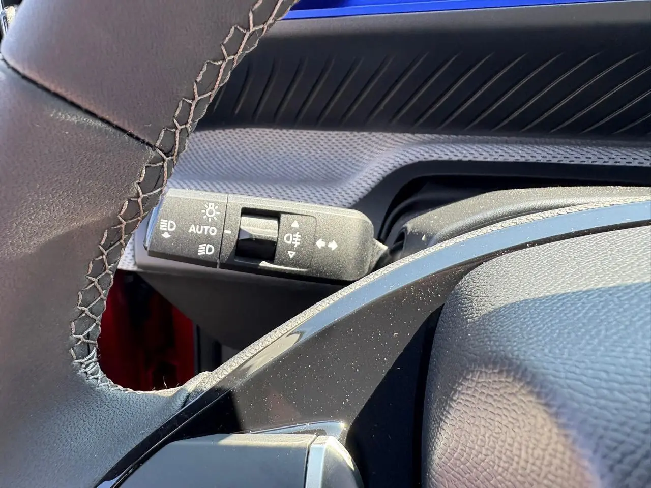 Gros plan sur la commande d'éclairage et clignotants à gauche du volant d'une Citroën C3 rouge Elixir toit noir.